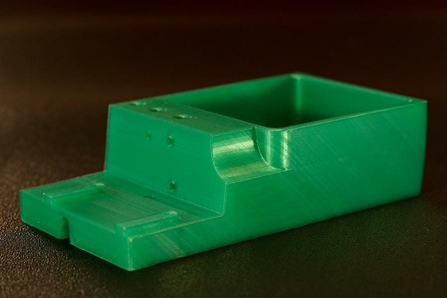 Grüne, 3D gedruckte Schale mit großer Vertiefung und seitlich mehreren Schraublöchern.