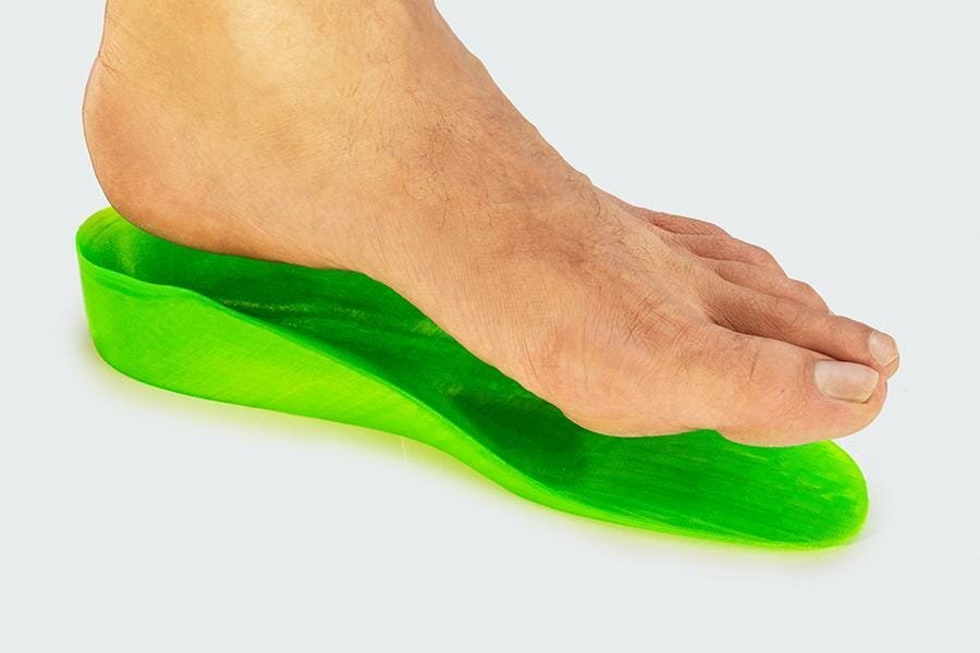 Fuß direkt über einer 3D gedruckten orthopädischen Einlegesohle, die genau auf die Formen des Fußes zugeschnitten ist.