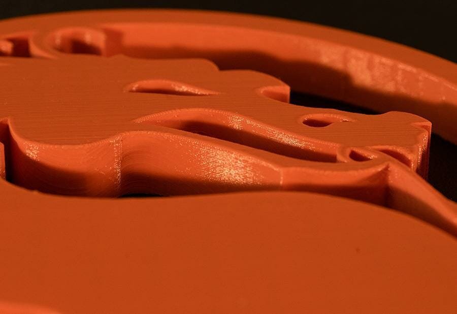Nahaufnahme eines feuerspeienden Drachen, Teil einem 3D gedruckten Emblems aus orangem PETG.