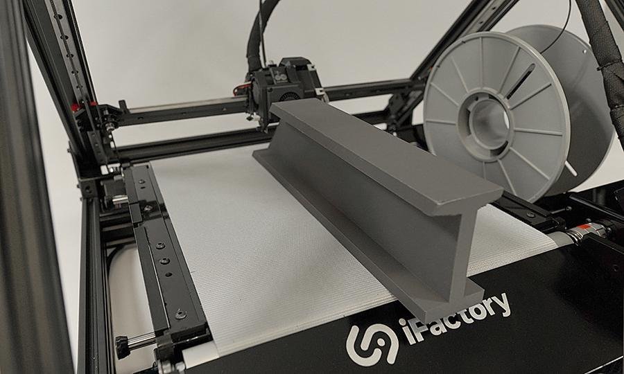The One Pro from iFactory3D printing a double-T steel beam model made of gray filament material, part of the print already protrudes over the scraper with brand inscription