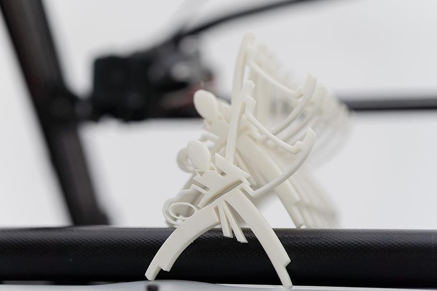 Abstract figures set up in a row representing karate fighters. Non-profit project for a sports club, as participants and winners badge made of white plastic material, in the background is blurred printing rail of One Pro