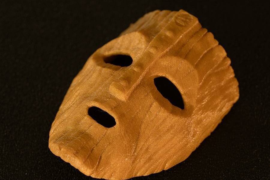 Golden mask with cutouts for eyes and mouth, covered with wood imitating texture