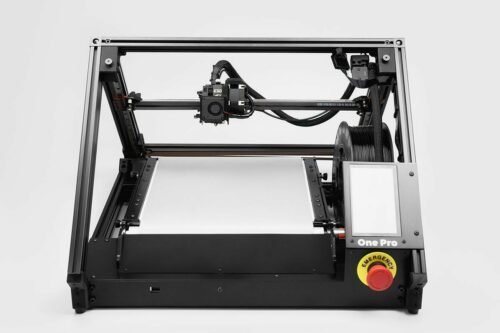 3D conveyor belt printer ONE PRO with pyramid-like structure, black frame and silver print bed; black filament spool in the build area, which is located just behind the display and emergency stop button